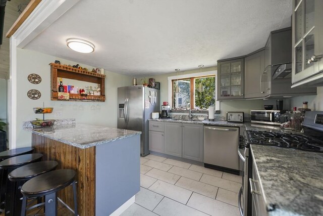 21 Hudson St, New Bedford, MA 02744 - kitchen with stainless steel appliances, gray cabinets, a peninsula, a breakfast bar, and a sink