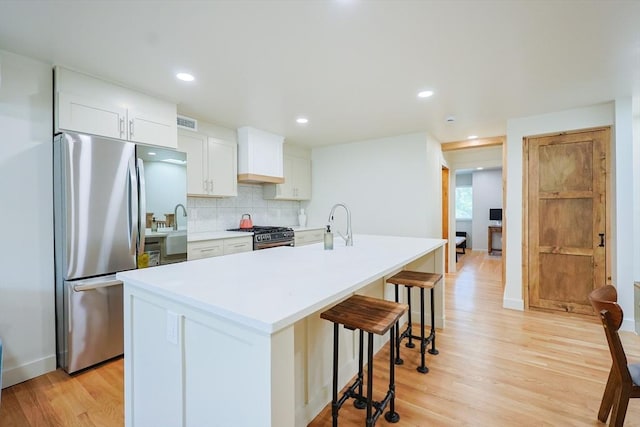 307 E Eagle St, Boston, MA 02128 - kitchen with stainless steel appliances, a kitchen bar, light wood-type flooring, backsplash, and an island with sink