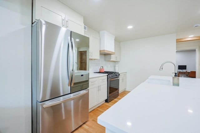 307 E Eagle St, Boston, MA 02128 - kitchen with appliances with stainless steel finishes, white cabinetry, decorative backsplash, light wood-style floors, and recessed lighting