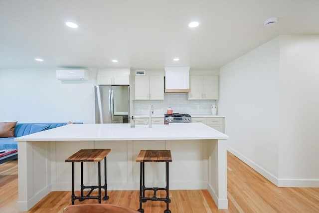 307 E Eagle St, Boston, MA 02128 - kitchen featuring stainless steel appliances, a wall unit AC, a kitchen bar, tasteful backsplash, and light wood-style floors