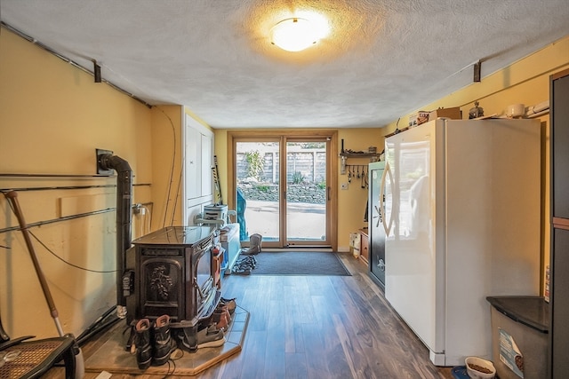 entryway featuring a textured ceiling, dark hardwood / wood-style floors, and a wood stove