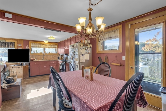 dining space featuring a notable chandelier, crown molding, light hardwood / wood-style flooring, and sink