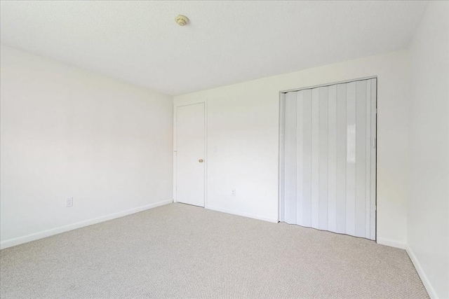 unfurnished bedroom featuring baseboards, carpet flooring, and a closet