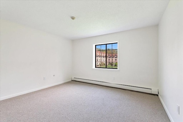 carpeted spare room featuring a baseboard heating unit and baseboards