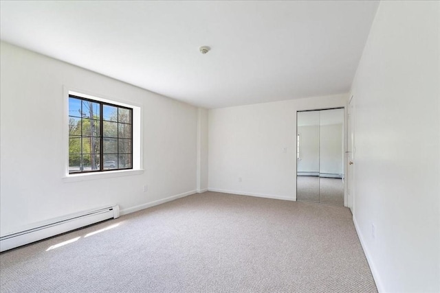 unfurnished room featuring carpet, baseboards, and a baseboard heating unit