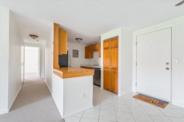 kitchen featuring stainless steel appliances, a sink, electric panel, brown cabinets, and light countertops