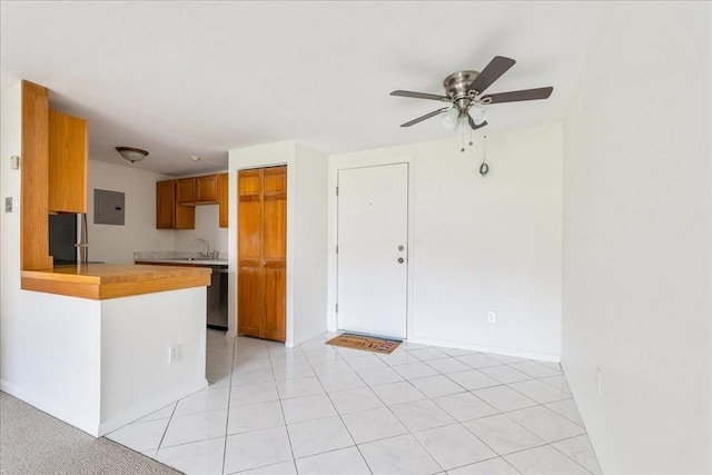 kitchen featuring ceiling fan, a sink, electric panel, brown cabinets, and light countertops