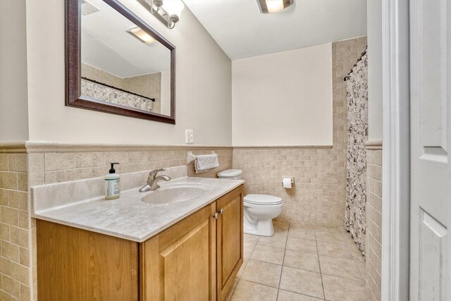 bathroom with tile patterned floors, vanity, tile walls, and toilet