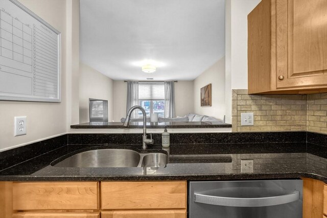 kitchen with tasteful backsplash, dishwasher, dark stone counters, and sink