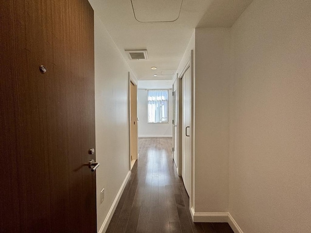 corridor featuring dark wood finished floors and baseboards