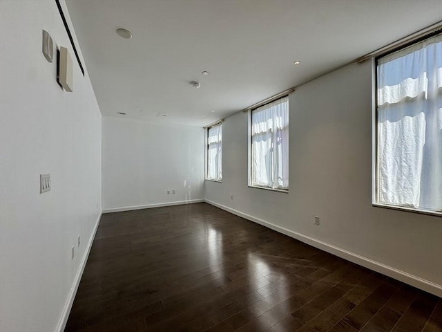 spare room featuring baseboards and dark wood finished floors