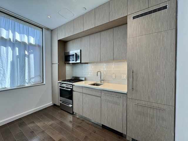 kitchen with appliances with stainless steel finishes, a sink, healthy amount of natural light, and light countertops