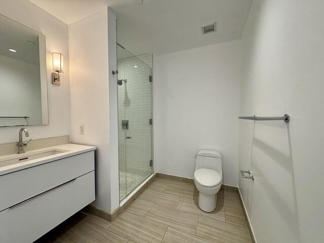 full bathroom with baseboards, a shower stall, toilet, and vanity
