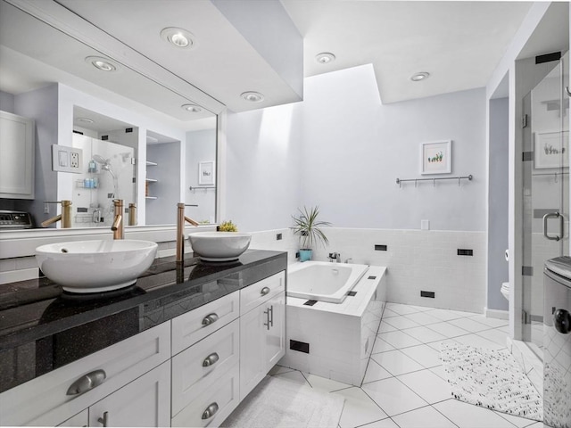 bathroom with a stall shower, a bath, double vanity, tile patterned floors, and recessed lighting
