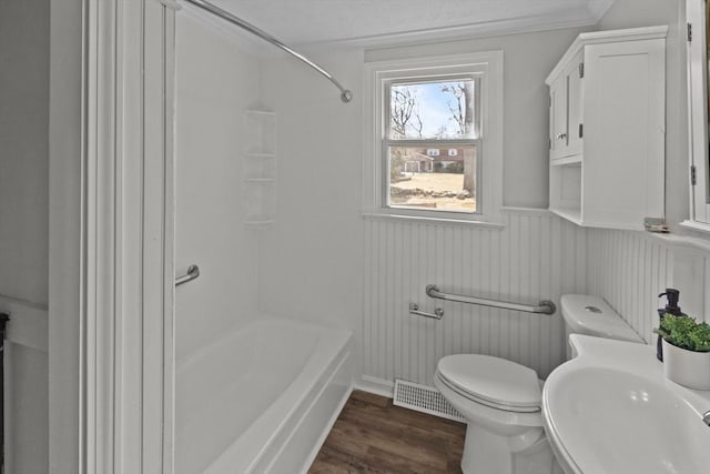 bathroom with visible vents, toilet, wainscoting, wood finished floors, and a sink