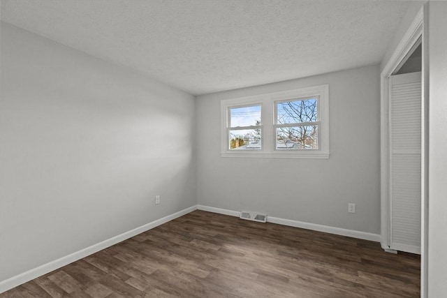 unfurnished bedroom featuring dark wood-type flooring, baseboards, visible vents, and a textured ceiling