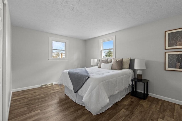 bedroom with visible vents, multiple windows, and dark wood-style flooring