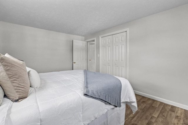 bedroom featuring a closet, baseboards, a textured ceiling, and wood finished floors