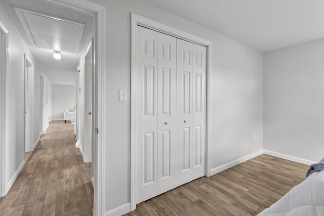 bedroom with a closet, baseboards, attic access, and wood finished floors