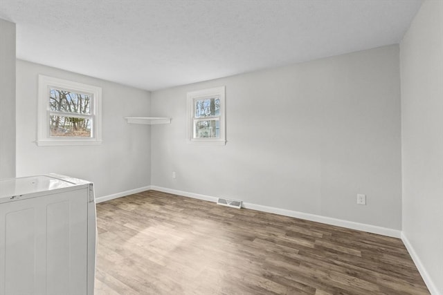 clothes washing area with visible vents, baseboards, laundry area, washer / dryer, and wood finished floors