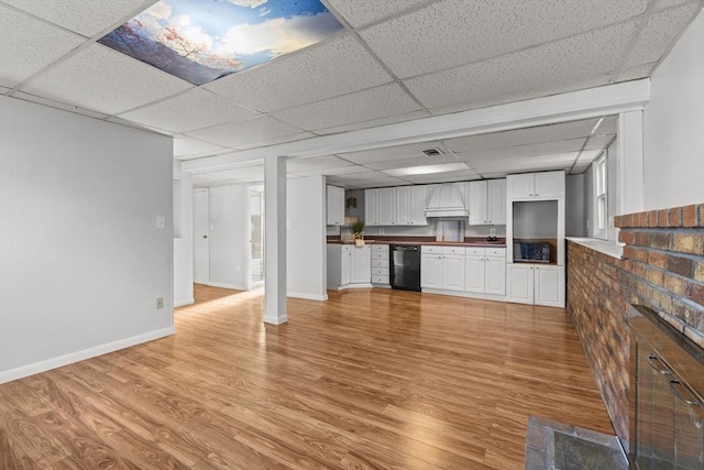 unfurnished living room featuring a drop ceiling, baseboards, visible vents, and light wood-style flooring