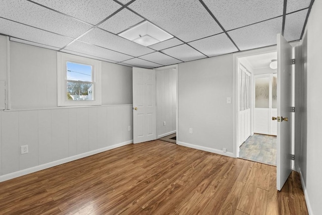 below grade area featuring wood finished floors, baseboards, and a paneled ceiling