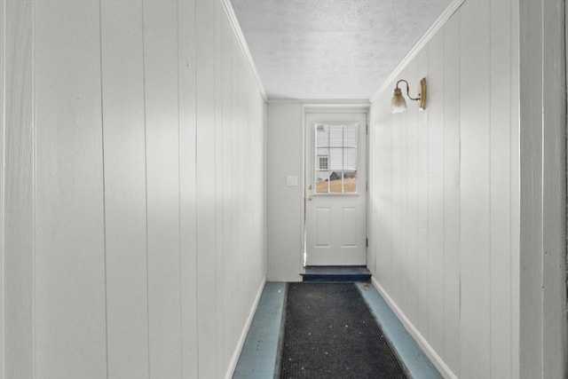 doorway featuring crown molding, baseboards, and a textured ceiling