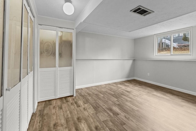 unfurnished bedroom with visible vents, baseboards, wood finished floors, and ornamental molding