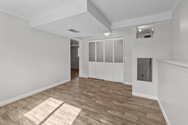 unfurnished room featuring wood finished floors, visible vents, and baseboards