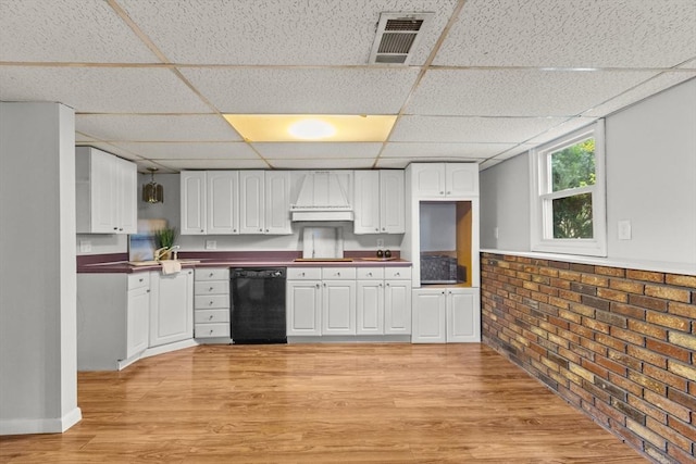 kitchen featuring light wood-type flooring, visible vents, black dishwasher, white cabinetry, and a paneled ceiling