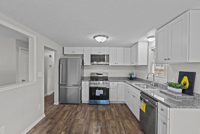 kitchen featuring light stone counters, white cabinetry, stainless steel appliances, and a sink