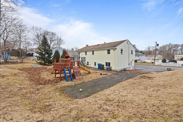 rear view of property with a chimney and a playground