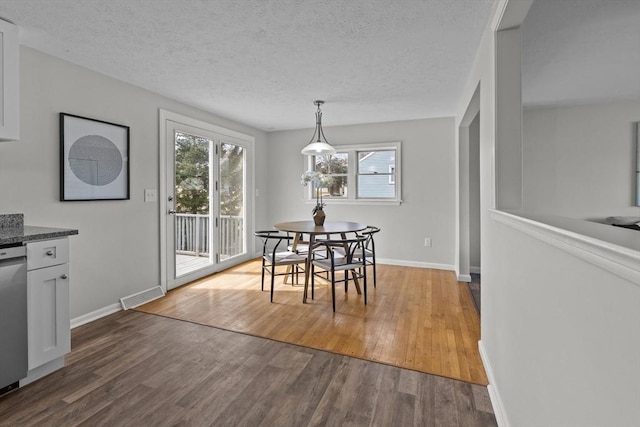 dining space with visible vents, a textured ceiling, and dark wood-style floors