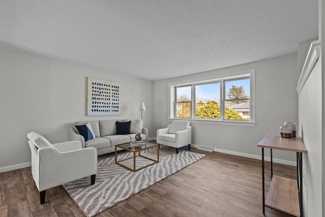 living area with a textured ceiling, baseboards, and wood finished floors