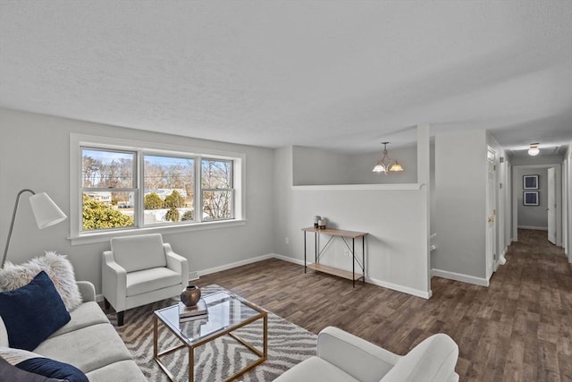 living area with baseboards, a textured ceiling, an inviting chandelier, and wood finished floors