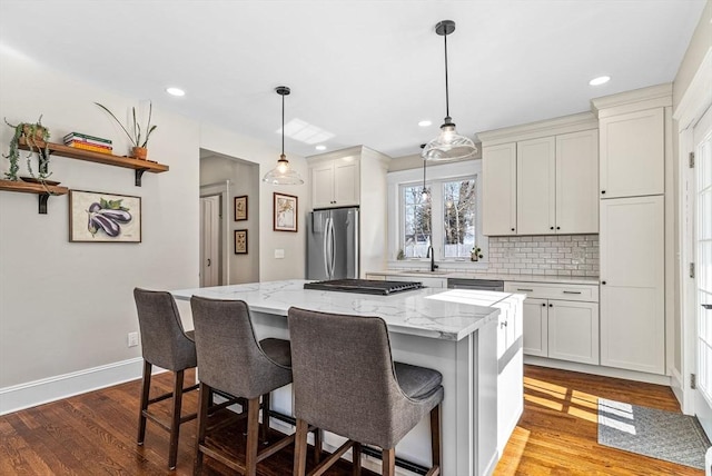 kitchen with a kitchen island, a breakfast bar, wood finished floors, freestanding refrigerator, and backsplash