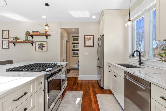 kitchen featuring a sink, white cabinets, appliances with stainless steel finishes, light stone countertops, and decorative light fixtures