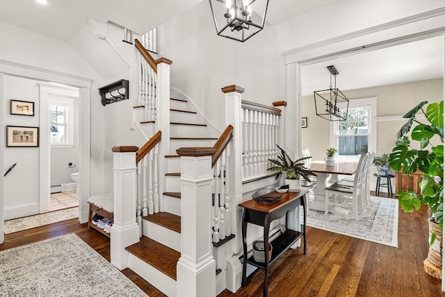 stairs with a baseboard radiator, baseboards, an inviting chandelier, and wood finished floors