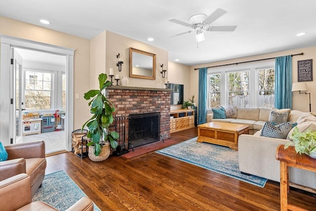 living area with ceiling fan, plenty of natural light, a fireplace, and wood finished floors