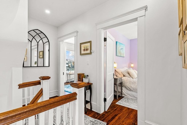 hallway featuring baseboards, dark wood-type flooring, and an upstairs landing