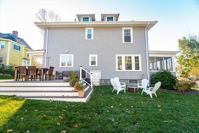 rear view of house featuring a deck, a yard, and an outdoor fire pit