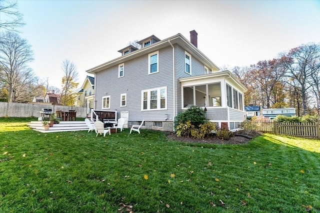 back of house with a sunroom, a chimney, fence, and a yard