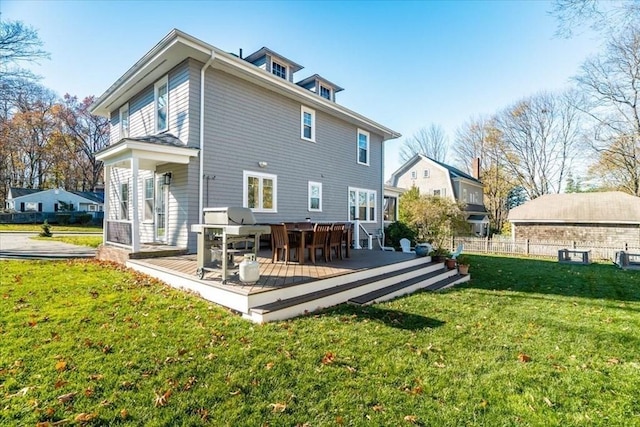 rear view of house featuring a yard, a wooden deck, and fence