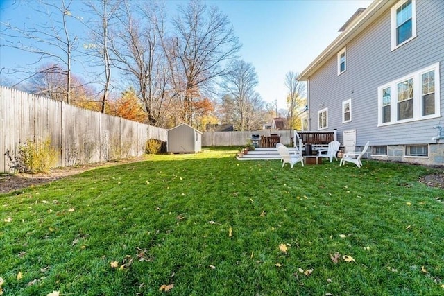 view of yard featuring an outbuilding, a fenced backyard, a wooden deck, and a shed