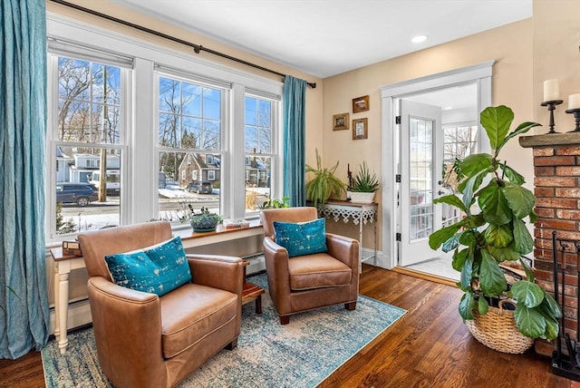 living area with baseboards, a baseboard heating unit, and wood finished floors