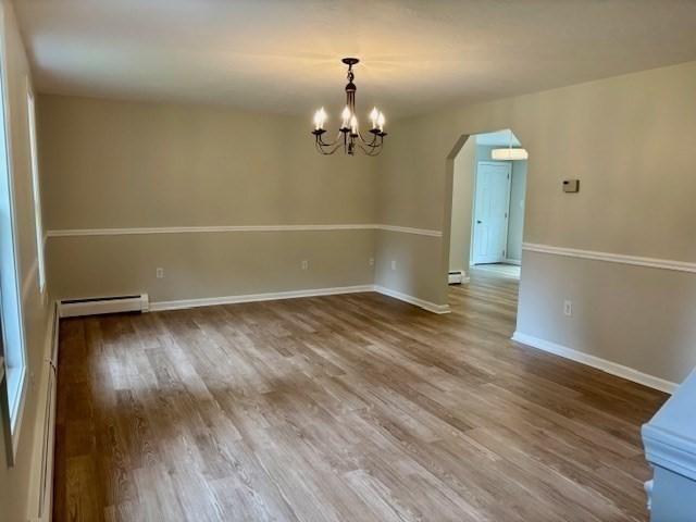 139 E County Rd Unit 139, Rutland, MA 01543 - unfurnished room featuring a baseboard heating unit, arched walkways, wood finished floors, a chandelier, and baseboards