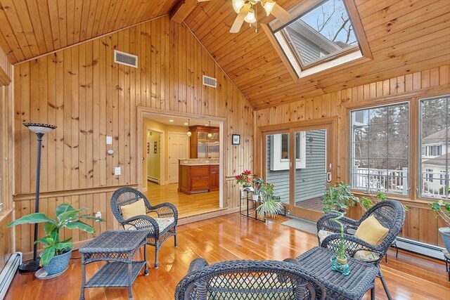 sunroom with a baseboard radiator, a baseboard heating unit, vaulted ceiling with skylight, and visible vents