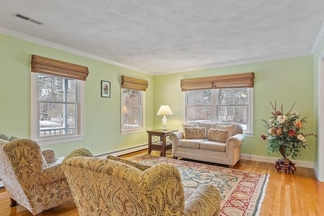 living area with a healthy amount of sunlight, visible vents, a baseboard heating unit, and wood finished floors