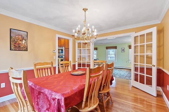 dining room with baseboard heating, light wood-type flooring, an inviting chandelier, and crown molding