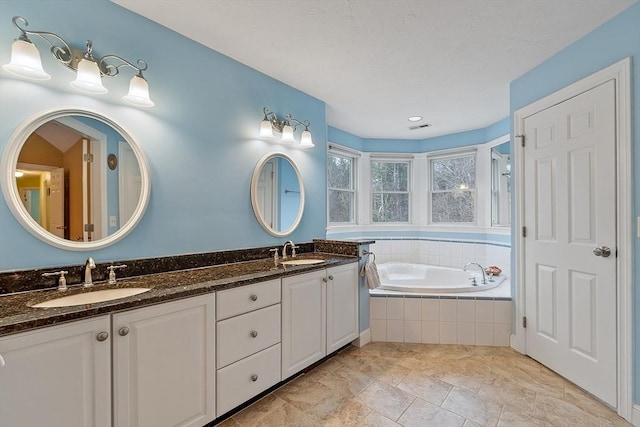 full bathroom featuring visible vents, double vanity, a sink, and a bath